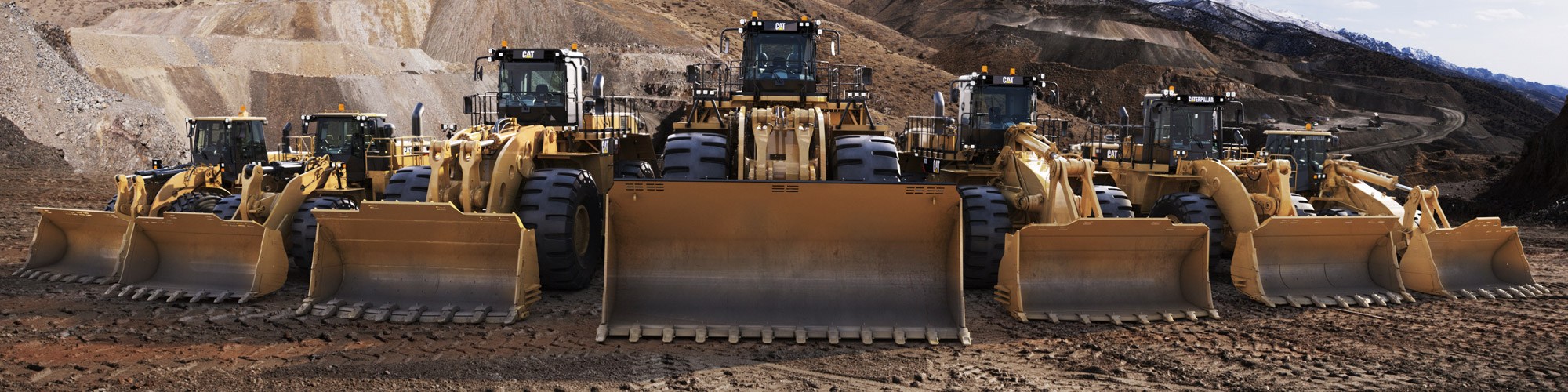 7 Cat Wheel Loaders/Front Loaders lined up in a mine on dirt